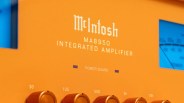 Close-up of an orange McIntosh MA8950 integrated amplifier panel with control knobs and a blue-lit meter.