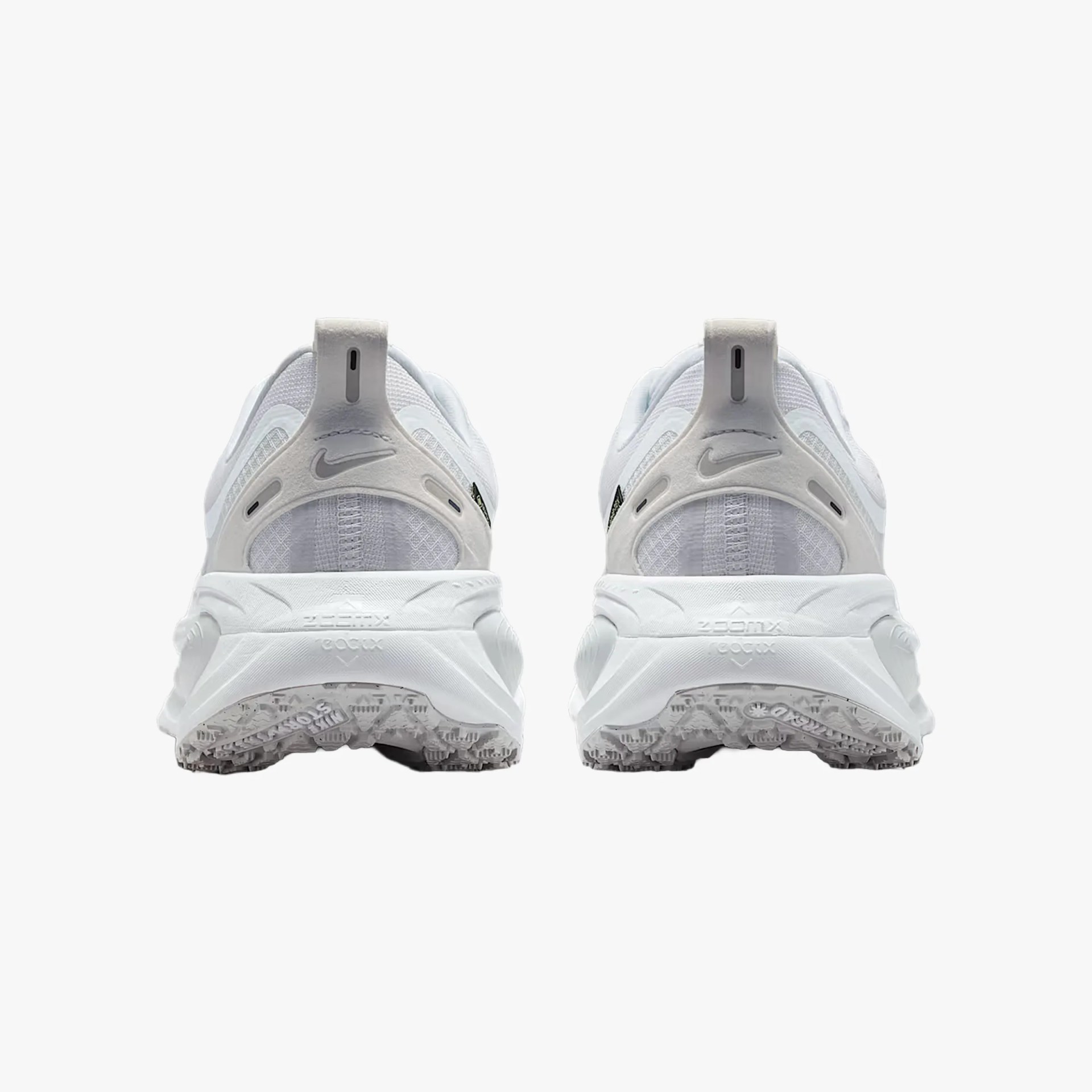 Pair of white Nike ZoomX running shoes shown from the back with textured soles and pull tabs.