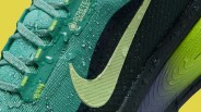 Close-up of a teal and black Nike shoe with a light green swoosh and water droplets on the surface.