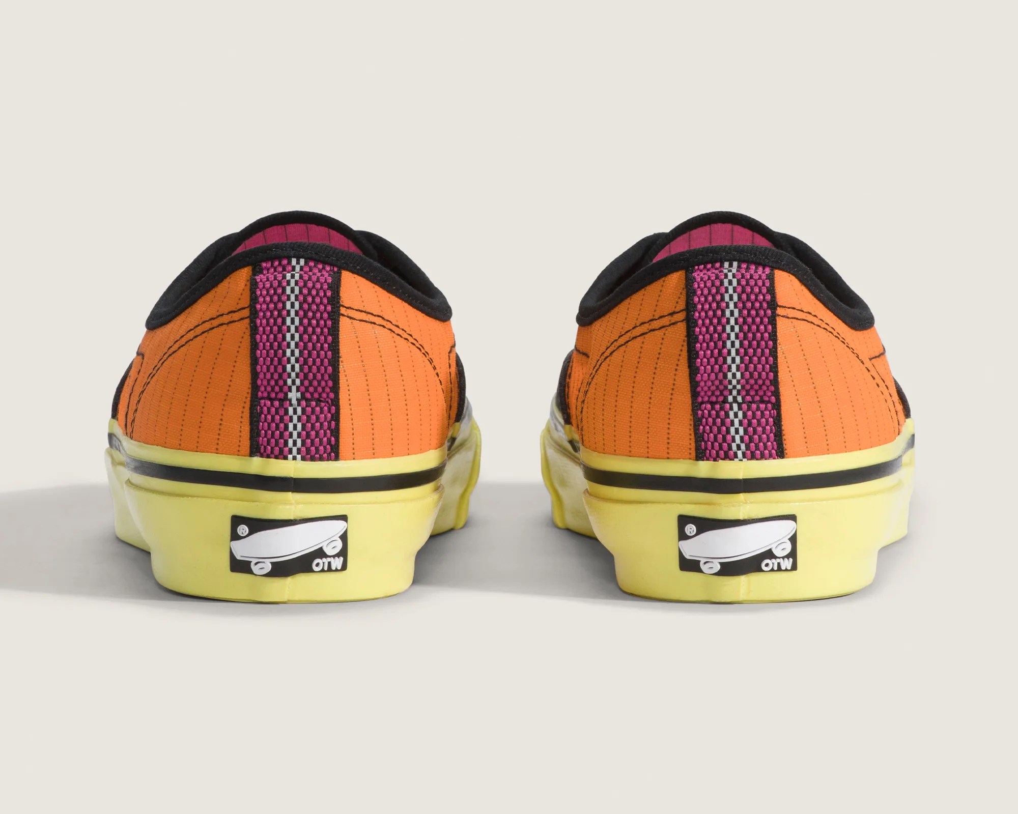 Pair of orange low-top sneakers with yellow soles and pink-black striped heel tabs, viewed from the back.
