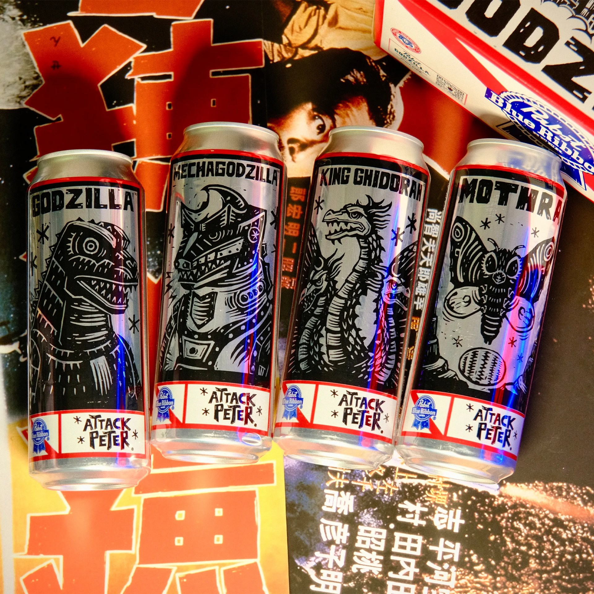 Four silver cans with black monster illustrations labeled Godzilla, Mechagodzilla, King Ghidorah, and Mothra, each with "Attack Peter" and a Pabst Blue Ribbon logo.