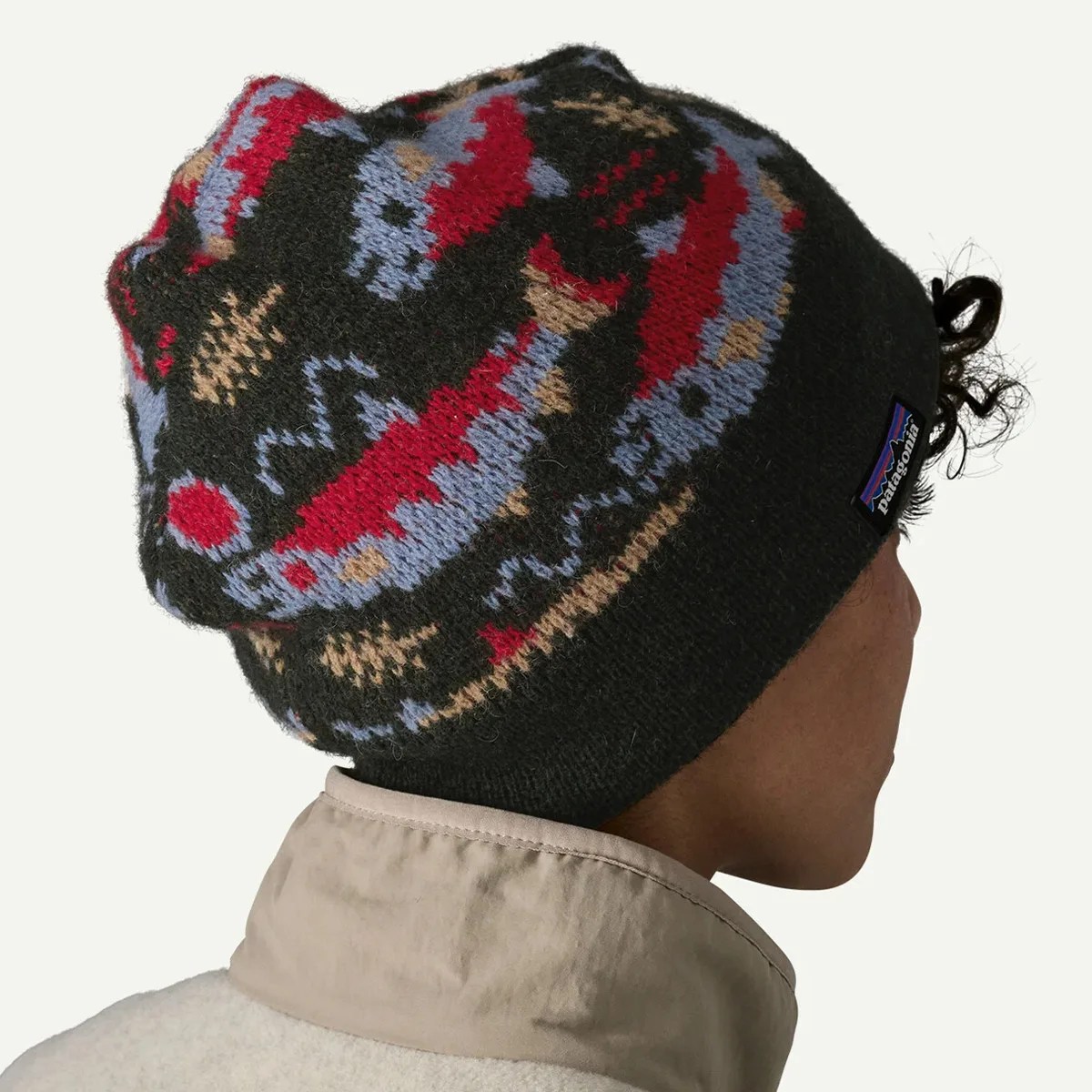 Black knit beanie with red, blue, and tan patterns and a Patagonia logo worn by a person.