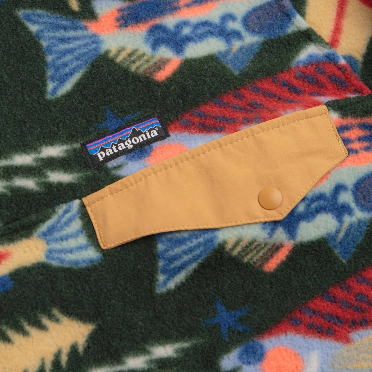 Close-up of a Patagonia fleece fabric with colorful fish patterns and a tan snap-button pocket flap.