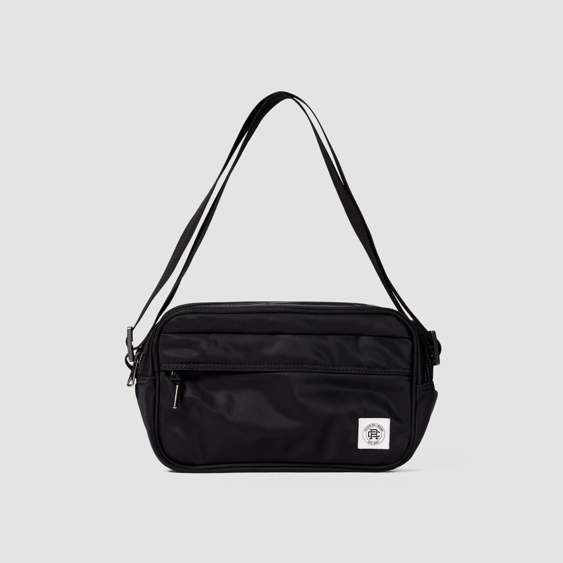 Black rectangular crossbody bag with front zipper pocket and white logo patch on bottom right.