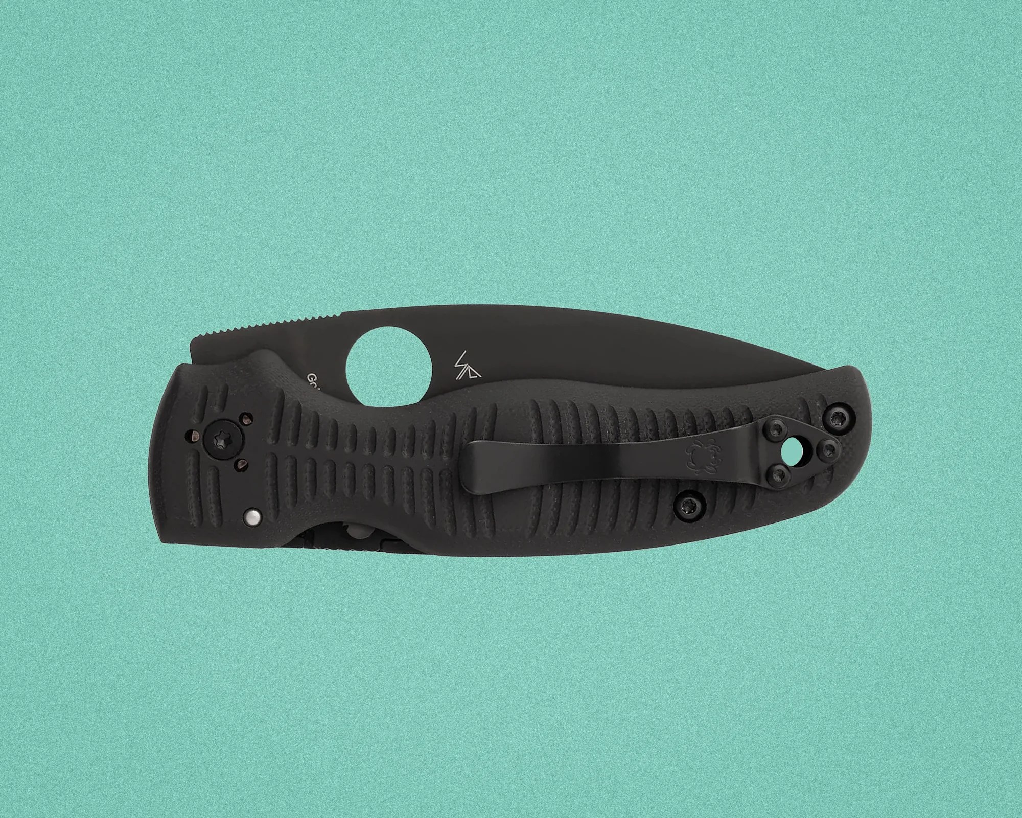 Folded black folding knife with textured handle and pocket clip on a teal background.