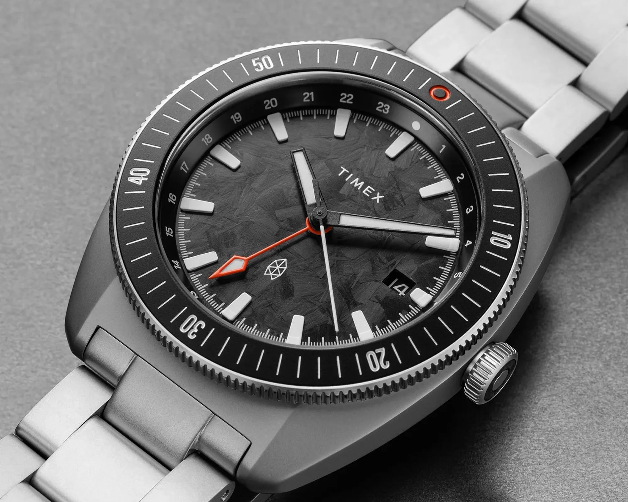 Silver Timex wristwatch with black textured dial, white hour markers, orange second hand, and metal link bracelet.