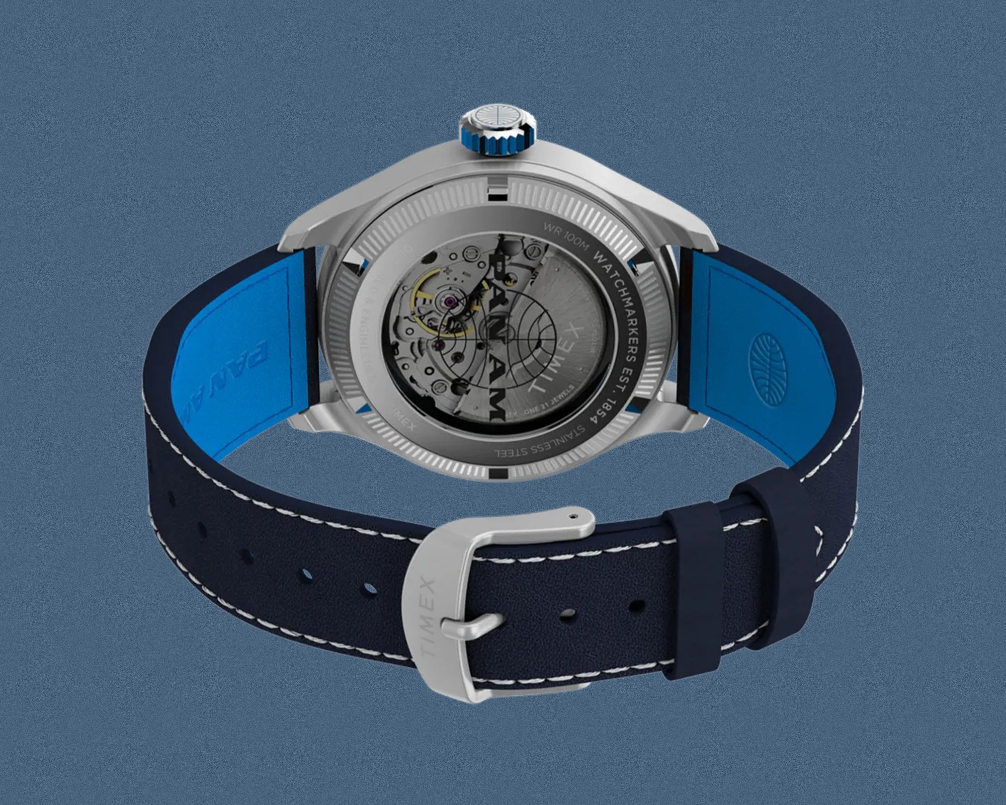 Stainless steel Timex watch with visible mechanical movement and navy blue leather strap with white stitching.