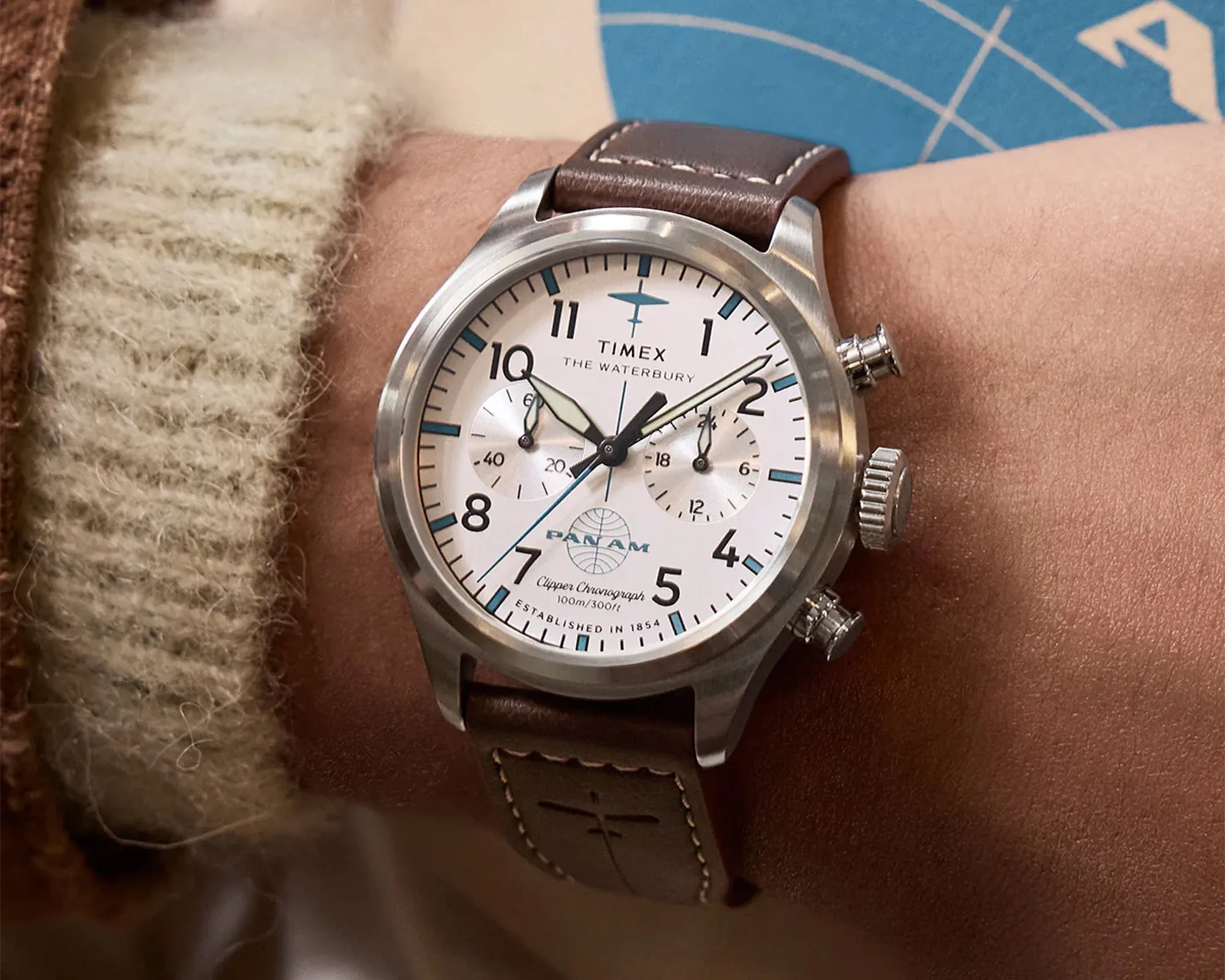 Timex Waterbury Pan Am chronograph watch with white dial and brown leather strap on a wrist.