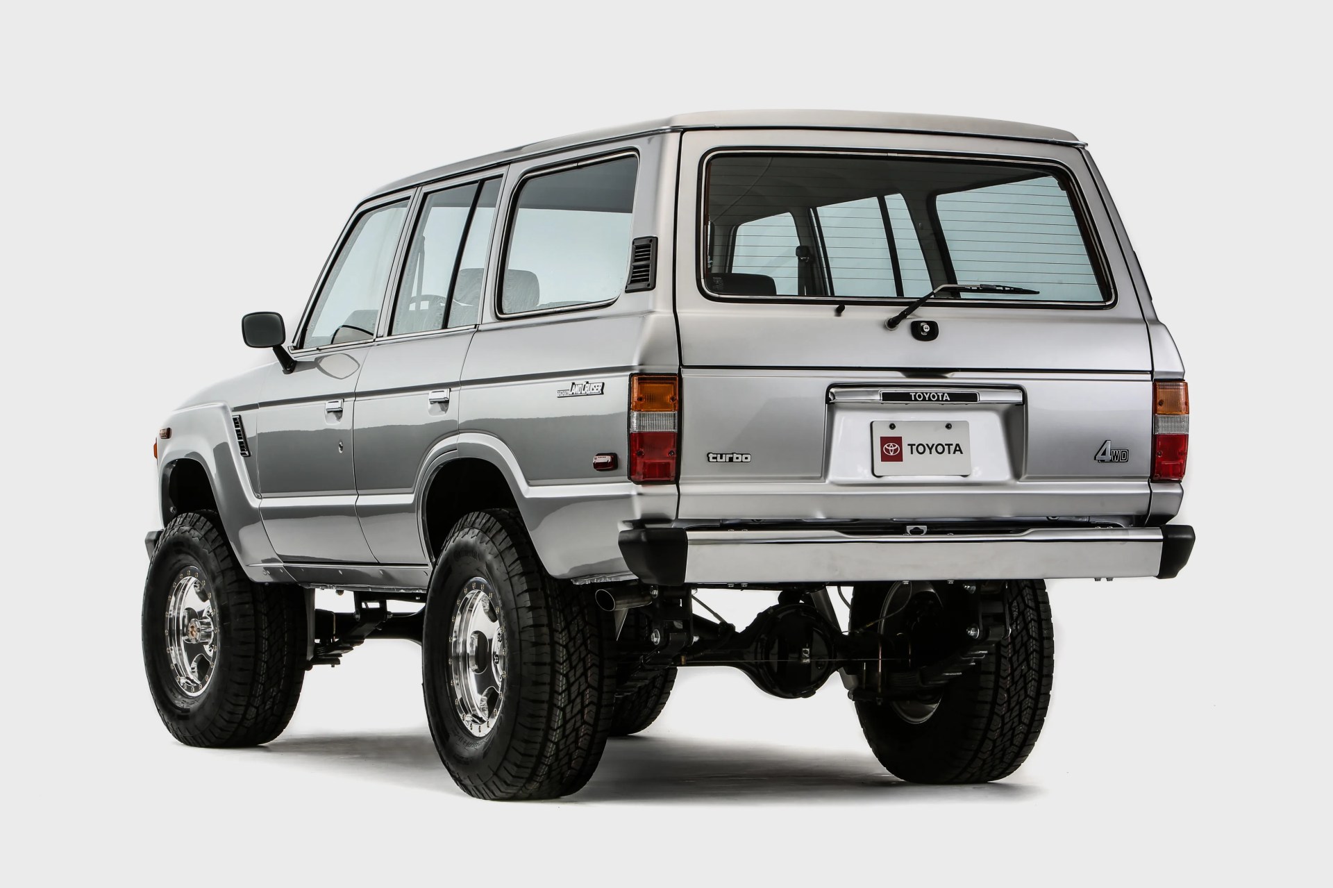 Silver Toyota Land Cruiser 4WD turbo SUV with raised suspension and large off-road tires, rear view.