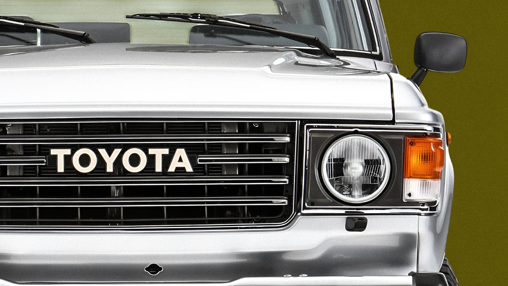 Front view of a silver Toyota vehicle with a black grille, round headlight, and orange turn signal.