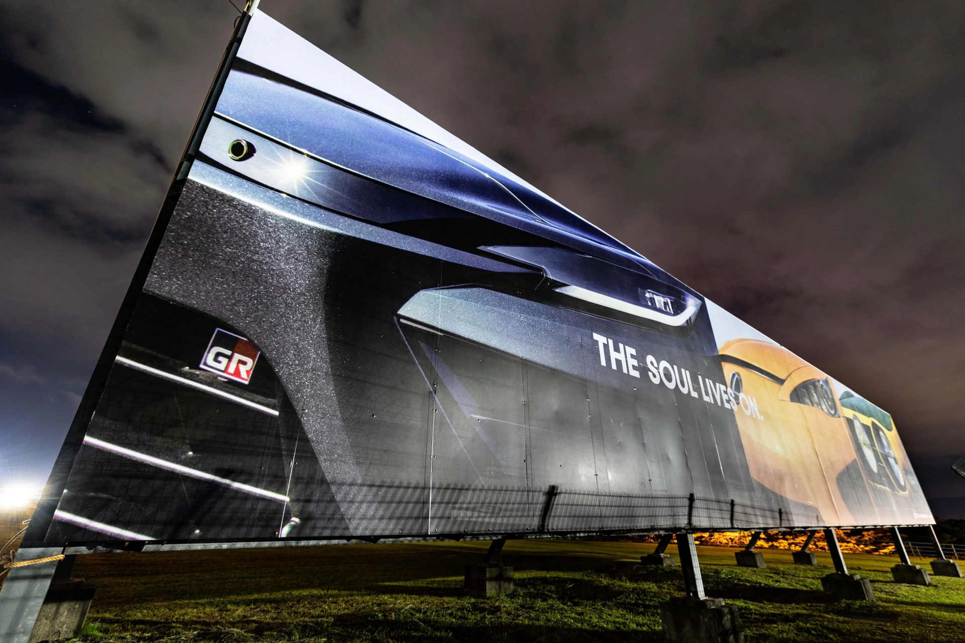 Large outdoor billboard at night showing close-up of a black car front with "THE SOUL LIVES ON." text.