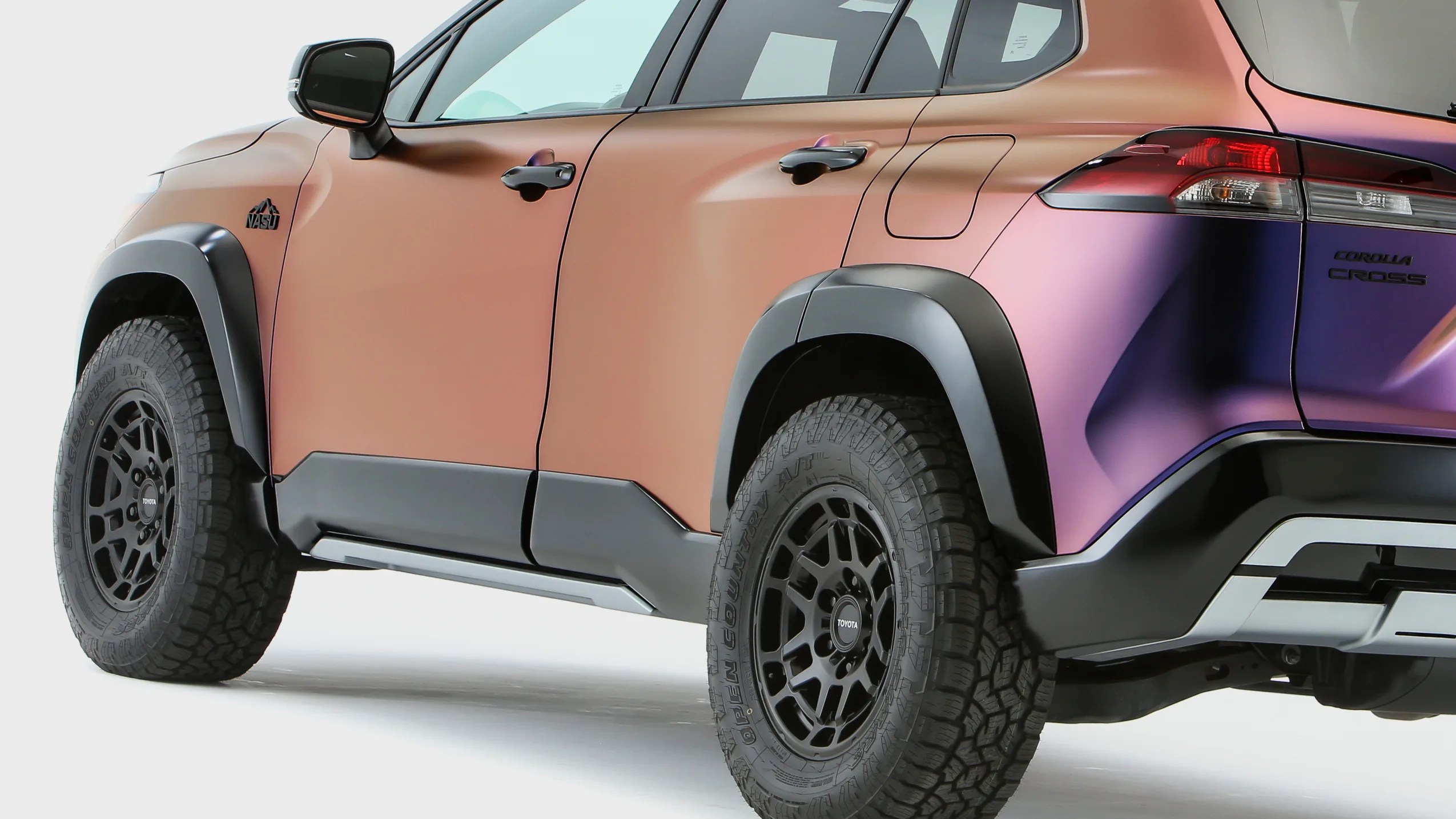 Rear side view of a Toyota Corolla Cross with matte orange to purple gradient paint and black off-road tires.