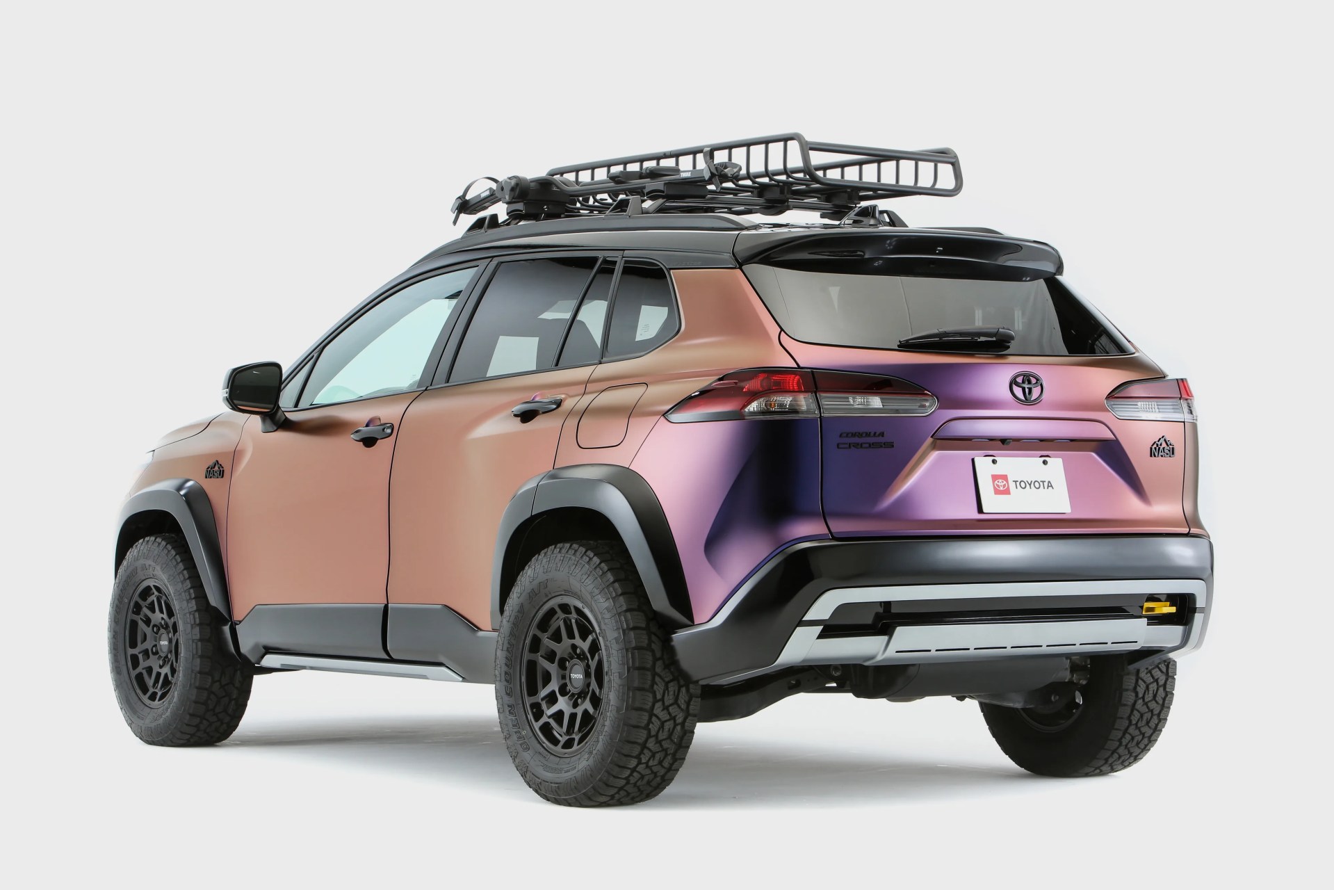 Toyota Corolla Cross SUV with a matte gradient finish from bronze to purple, black roof rack, and off-road tires.