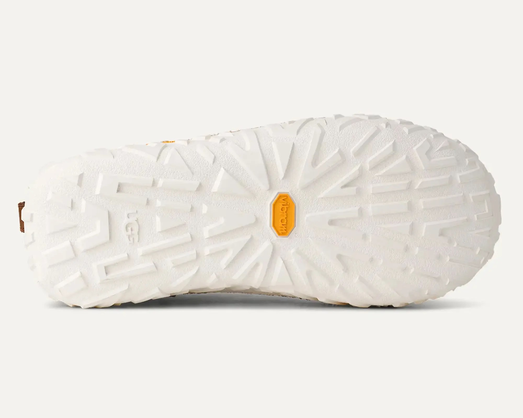 White rubber shoe sole with deep tread pattern and yellow Vibram logo in the center.