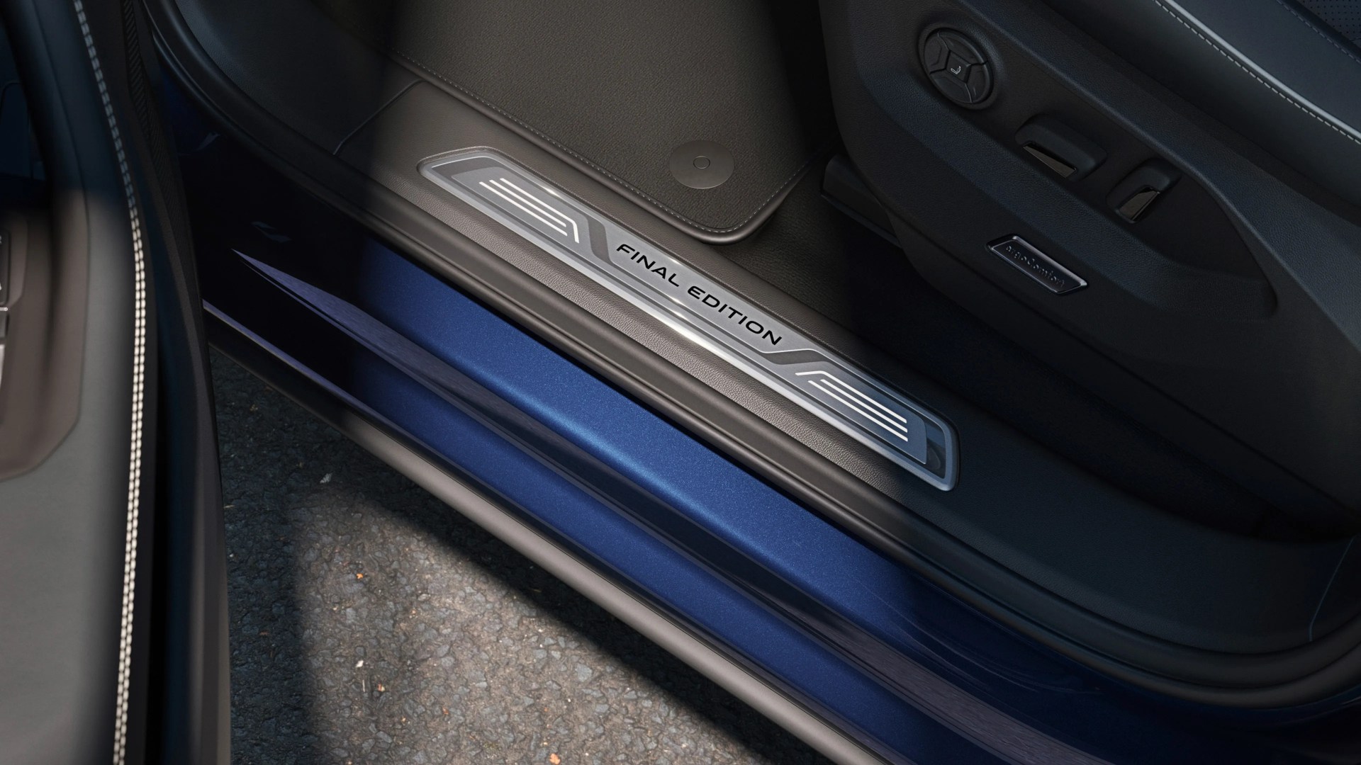 Car door sill plate with "FINAL EDITION" text in black on a silver metal strip, surrounded by black interior trim.