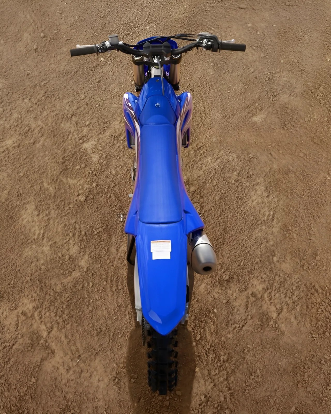 Blue dirt bike with knobby tires on a dirt track, viewed from above.