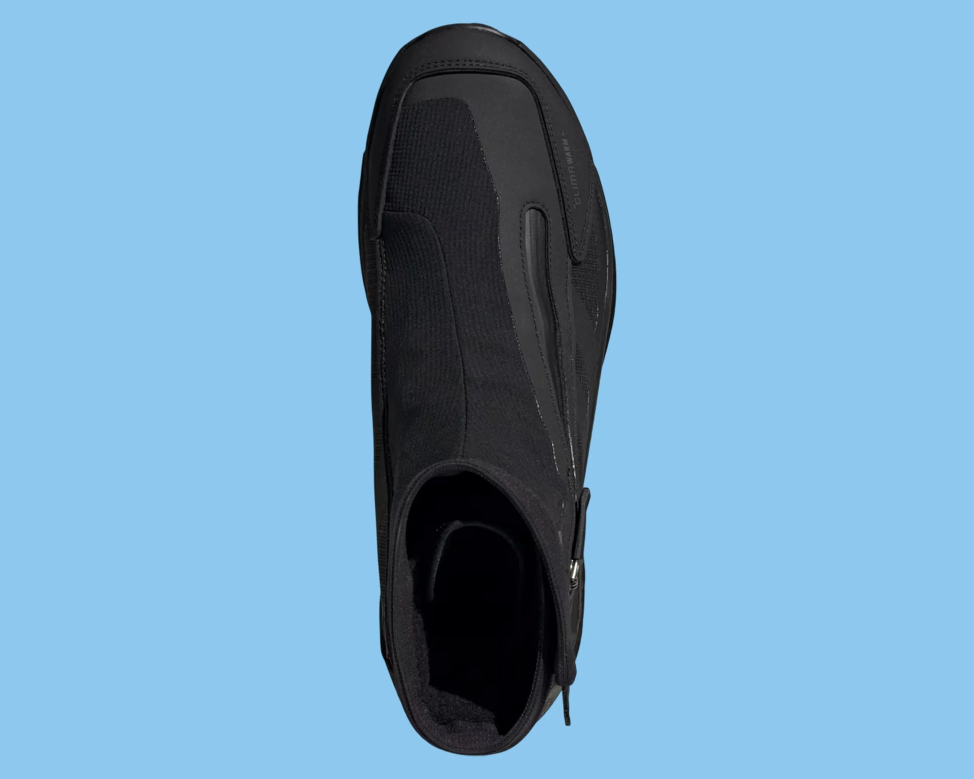 Black slip-on athletic shoe with zipper on side and textured fabric upper against blue background.