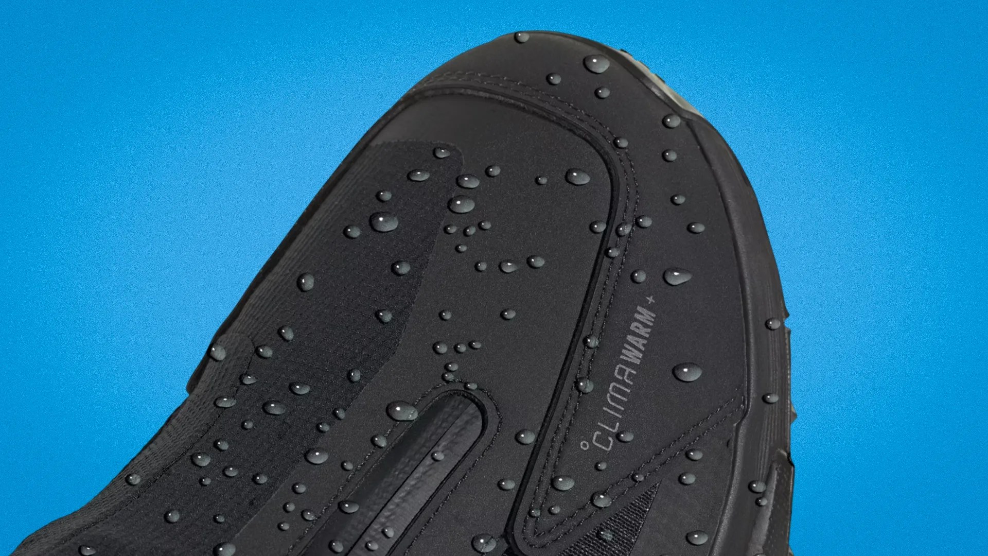 Close-up of a black waterproof shoe toe with water droplets and "Climawarm" branding on a blue background.