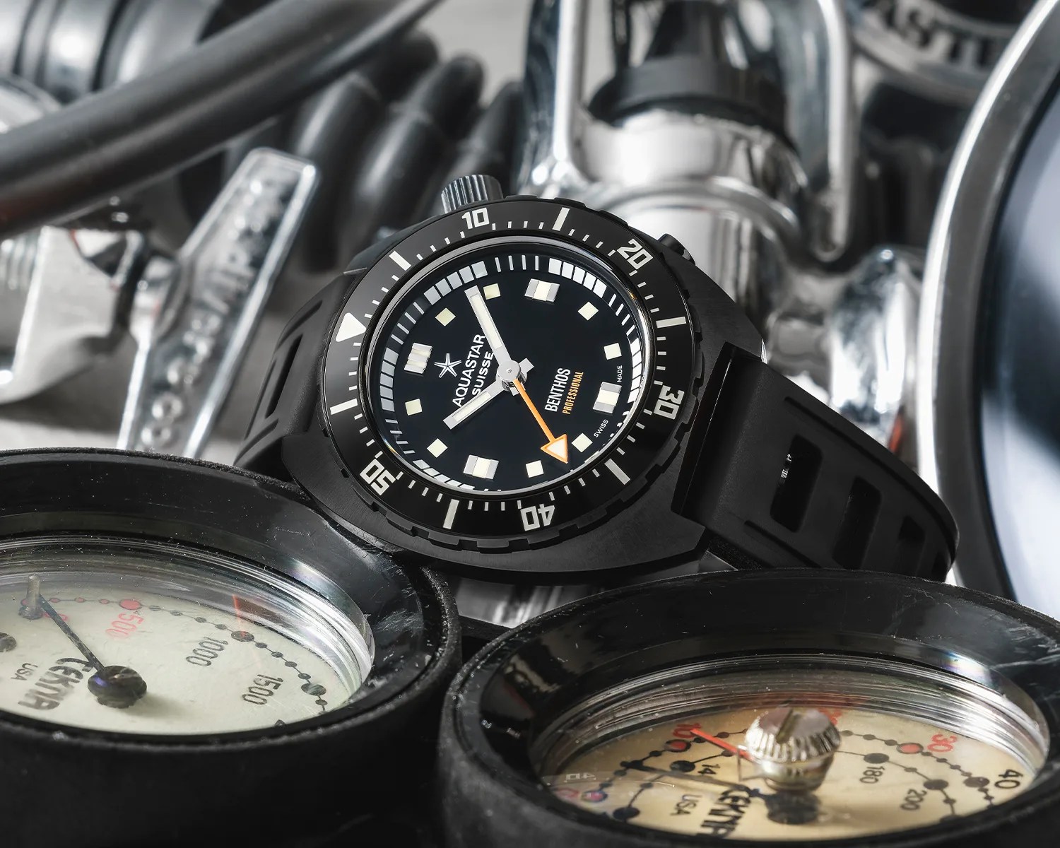 Black Aquastar Benthos Professional dive watch with orange arrow hand on black rubber strap, placed on diving gauges.