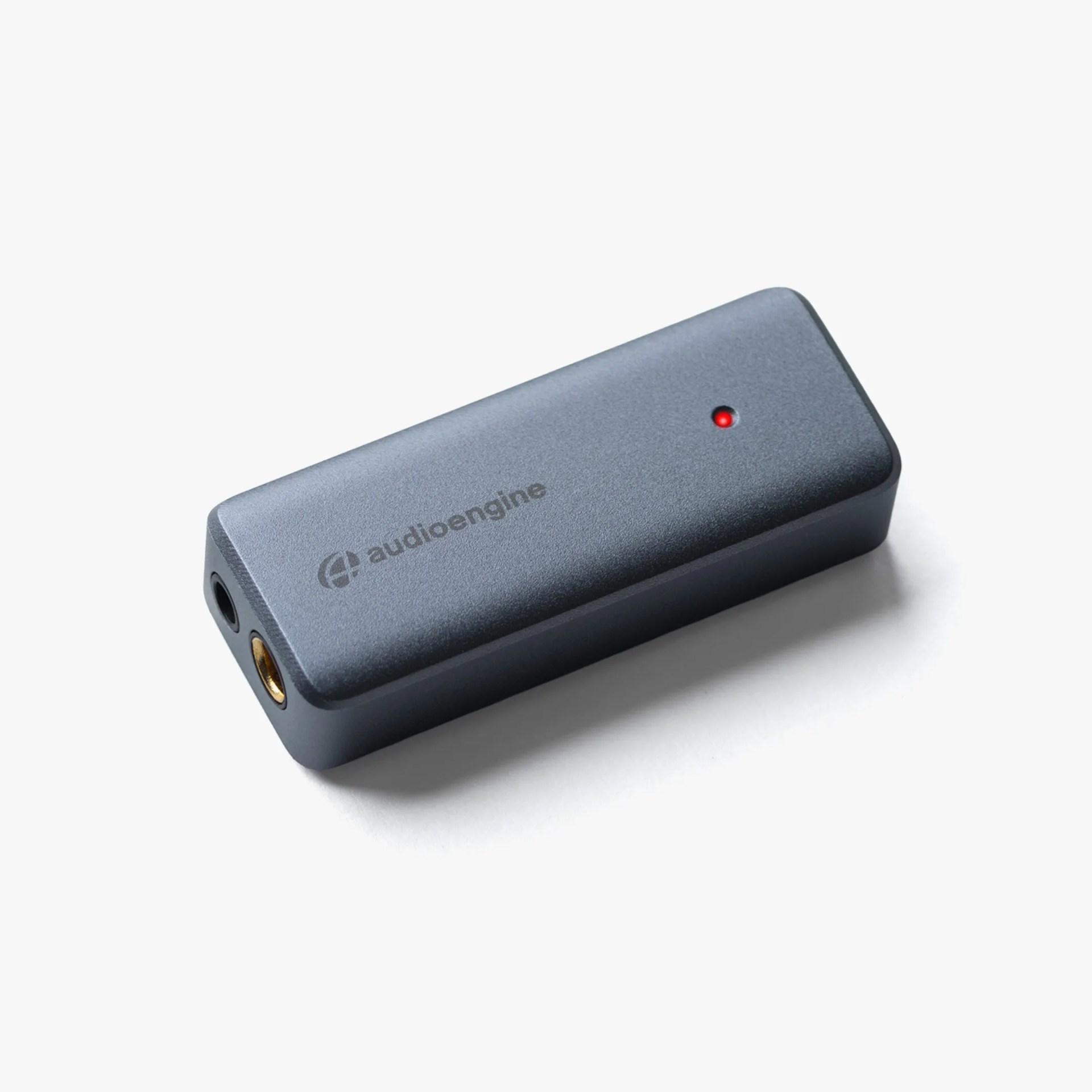 Rectangular dark gray Audioengine device with a red indicator light and two audio ports on one end.