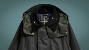 Dark green waxed cotton jacket with black corduroy collar and plaid inner lining.