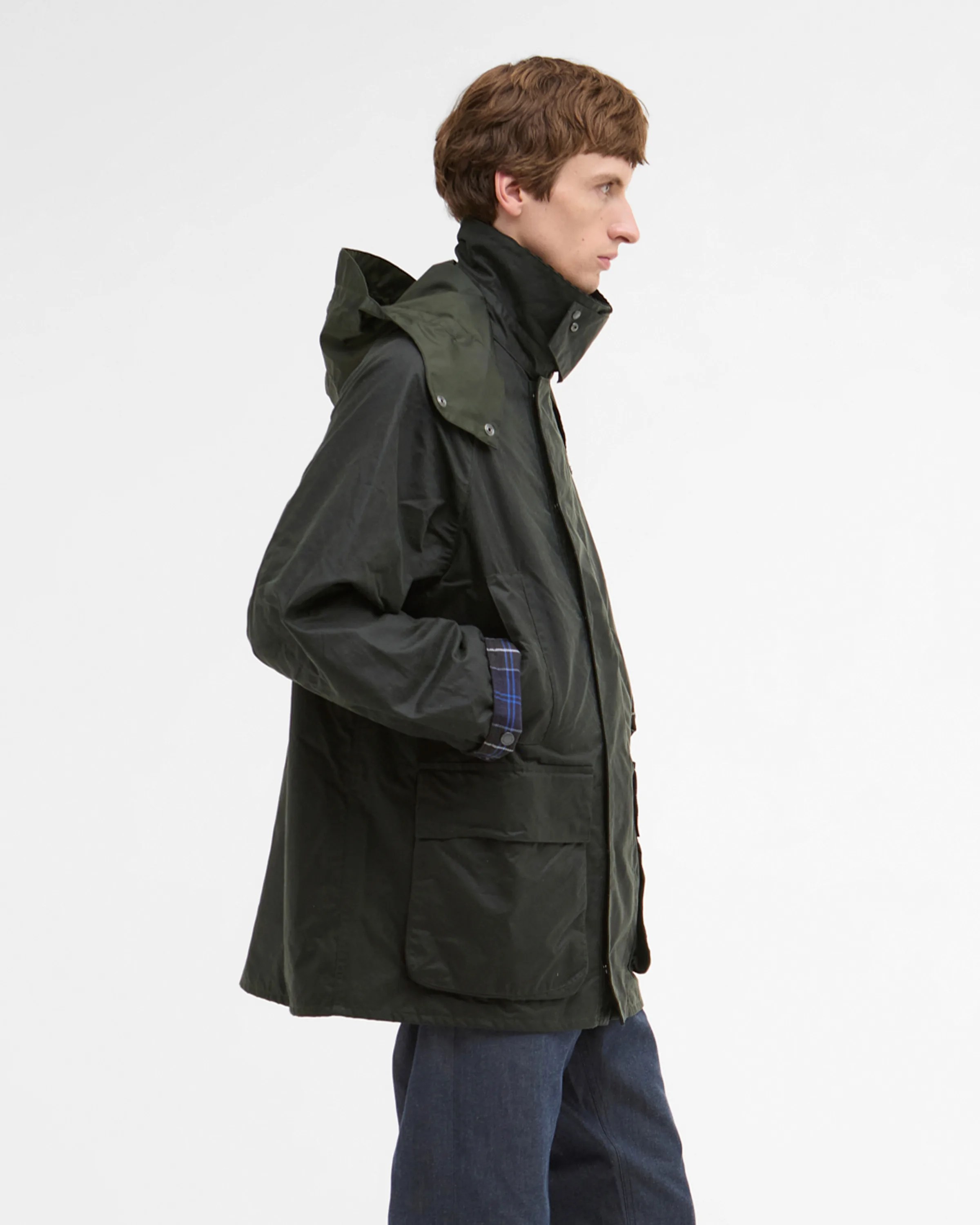Dark green hooded jacket with large front pockets worn by a person in blue pants.