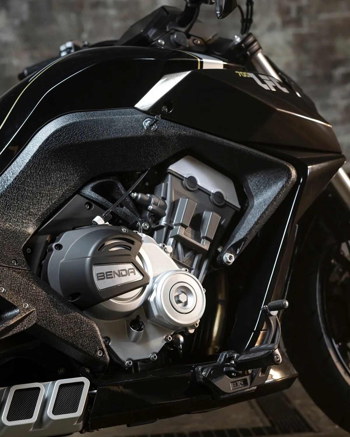 Close-up of a black motorcycle engine with "BENDA" branding on the engine cover and textured black frame panels.