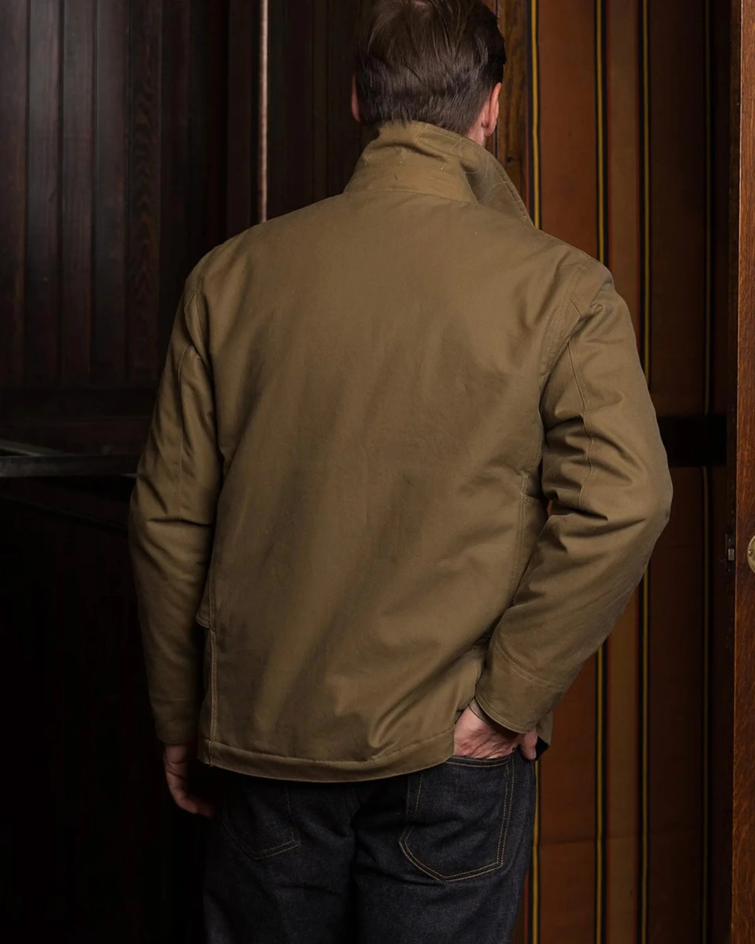 Man wearing a brown canvas jacket with a high collar, seen from the back.