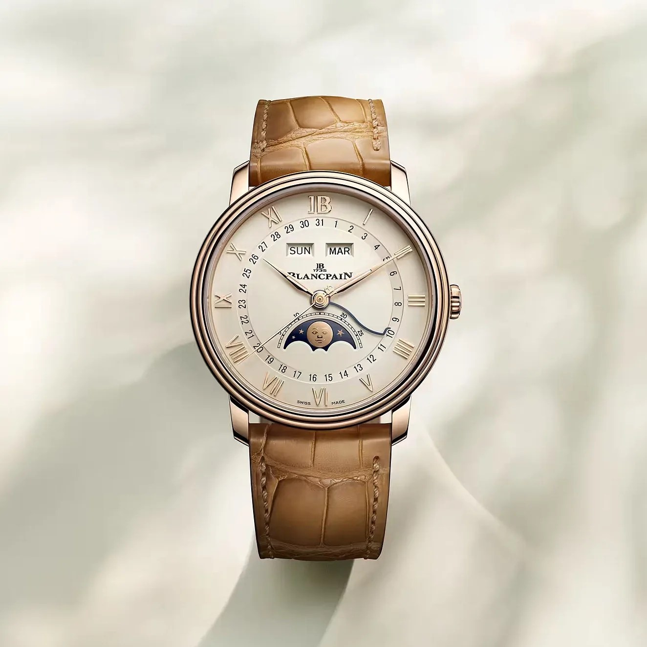 Round gold Blancpain wristwatch with beige dial, moon phase display, Roman numerals, and tan leather strap.