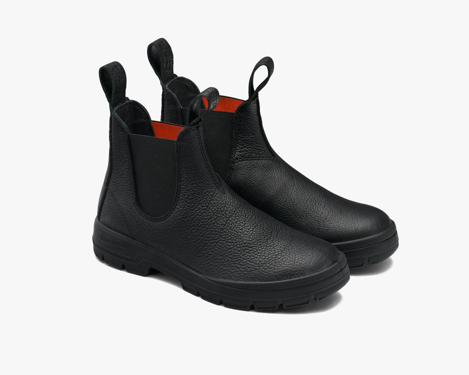 Pair of black textured leather Chelsea boots with black elastic side panels and orange interior lining.