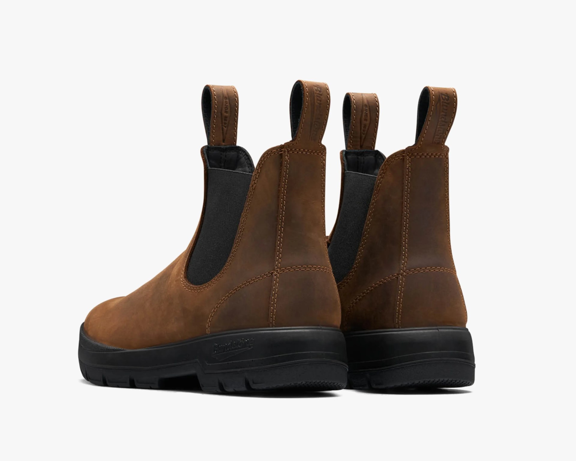 Pair of brown leather Chelsea boots with black elastic side panels and black rubber soles, viewed from the back.