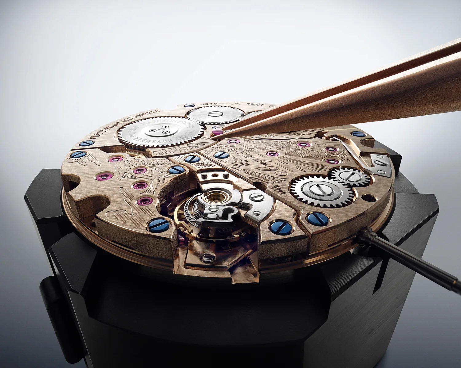 Close-up of a gold watch movement with blue screws and purple jewels held by a black clamp, tweezers adjusting a jewel.
