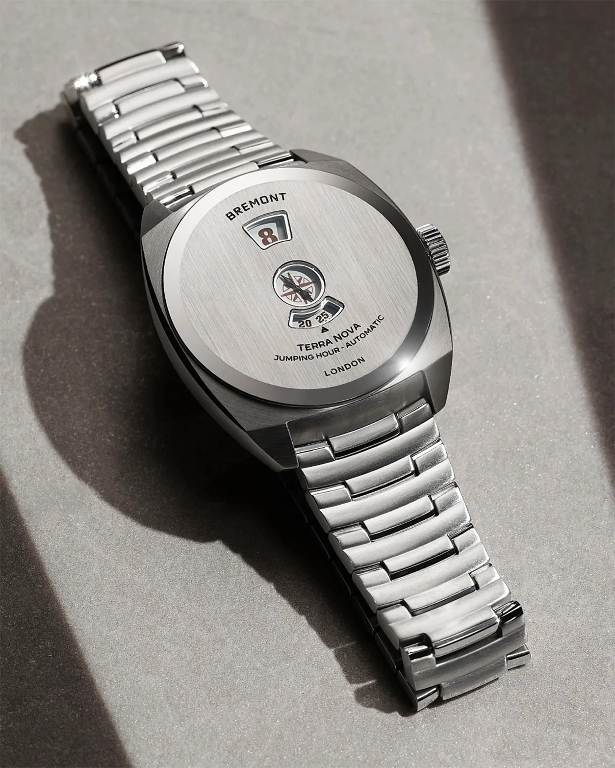 Silver Bremont Terra Nova wristwatch with a brushed metal face and linked metal bracelet on a gray surface.