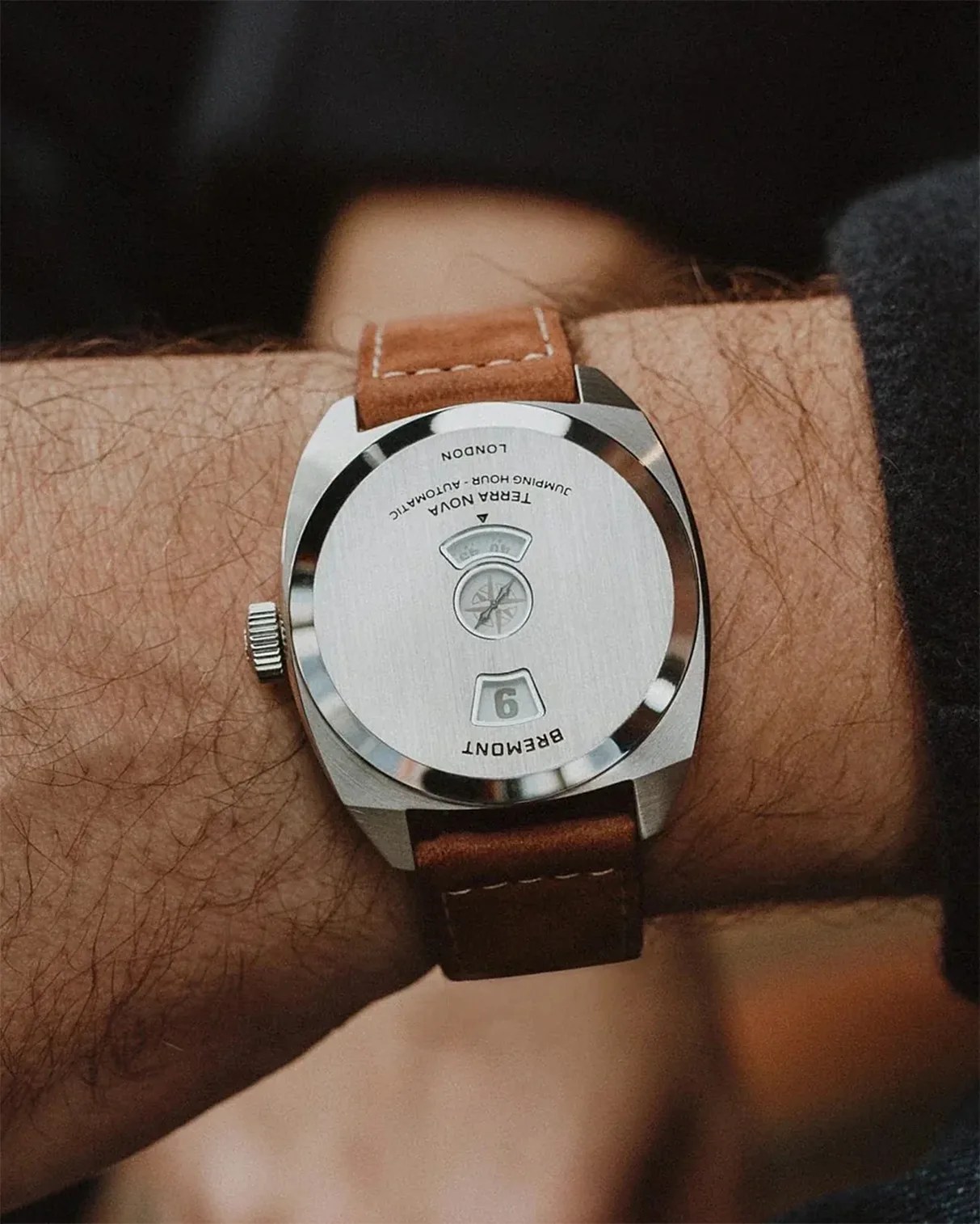 Silver Bremont Terra Nova watch with brown leather strap worn on a wrist, showing the back case.