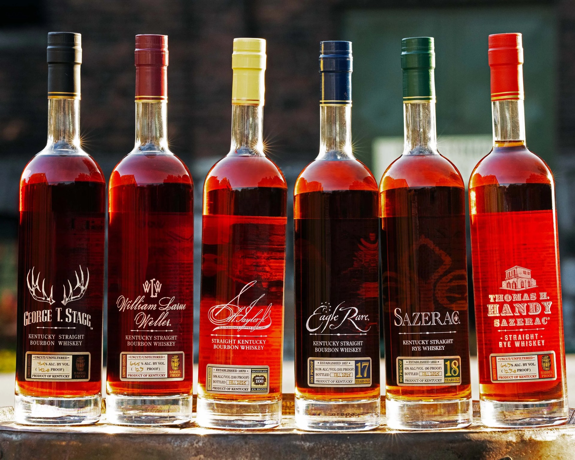Six bottles of Kentucky straight bourbon and rye whiskey with different colored caps (black, red, yellow, blue, green, orange) lined up on a surface.