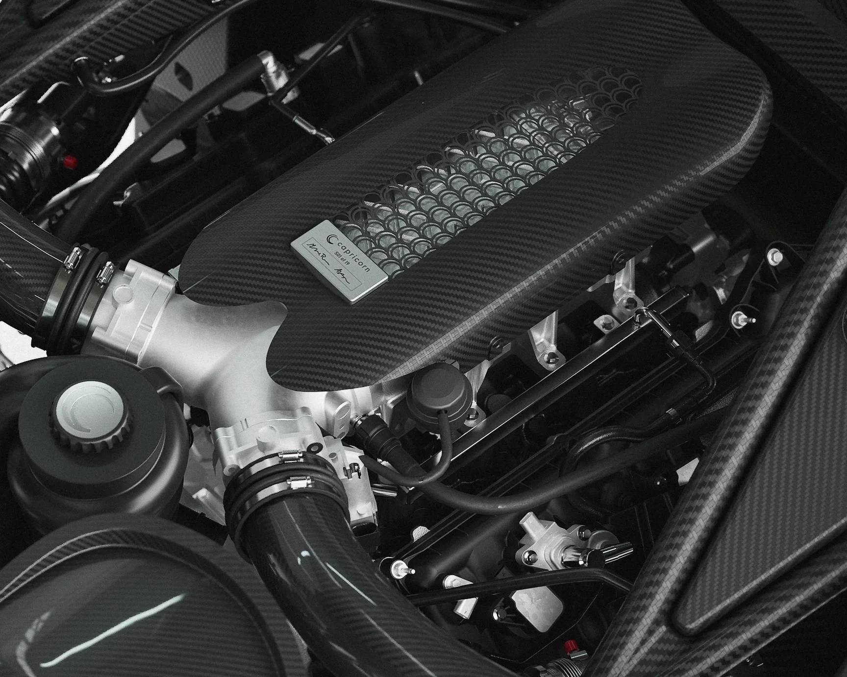 Carbon fiber engine cover with a metal badge labeled "Capricorn" on a high-performance car engine.