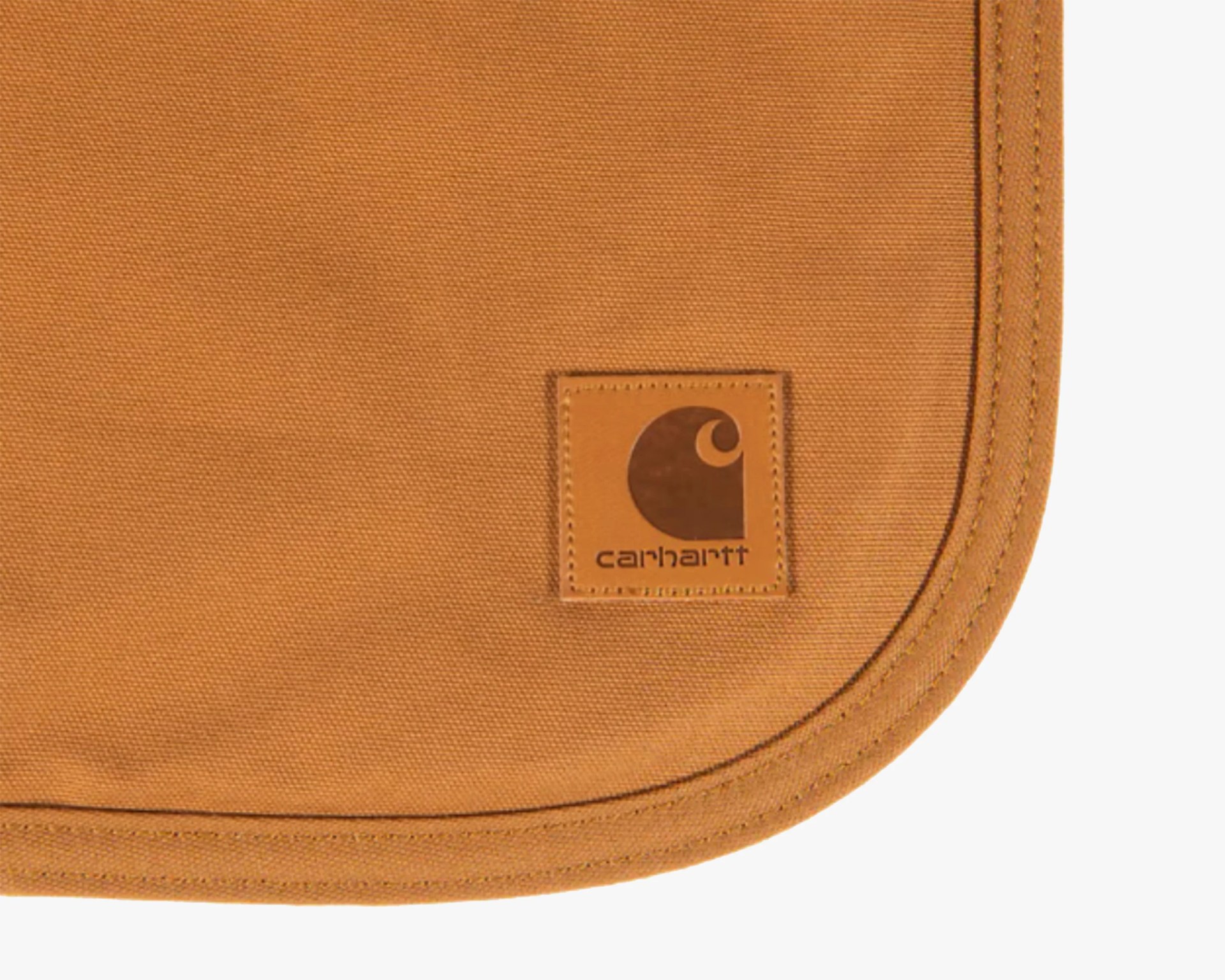 Close-up of a brown Carhartt fabric with a stitched leather logo patch on the corner.