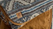 Folded Carhartt blanket with blue, gray, and white geometric patterns and brown trim.