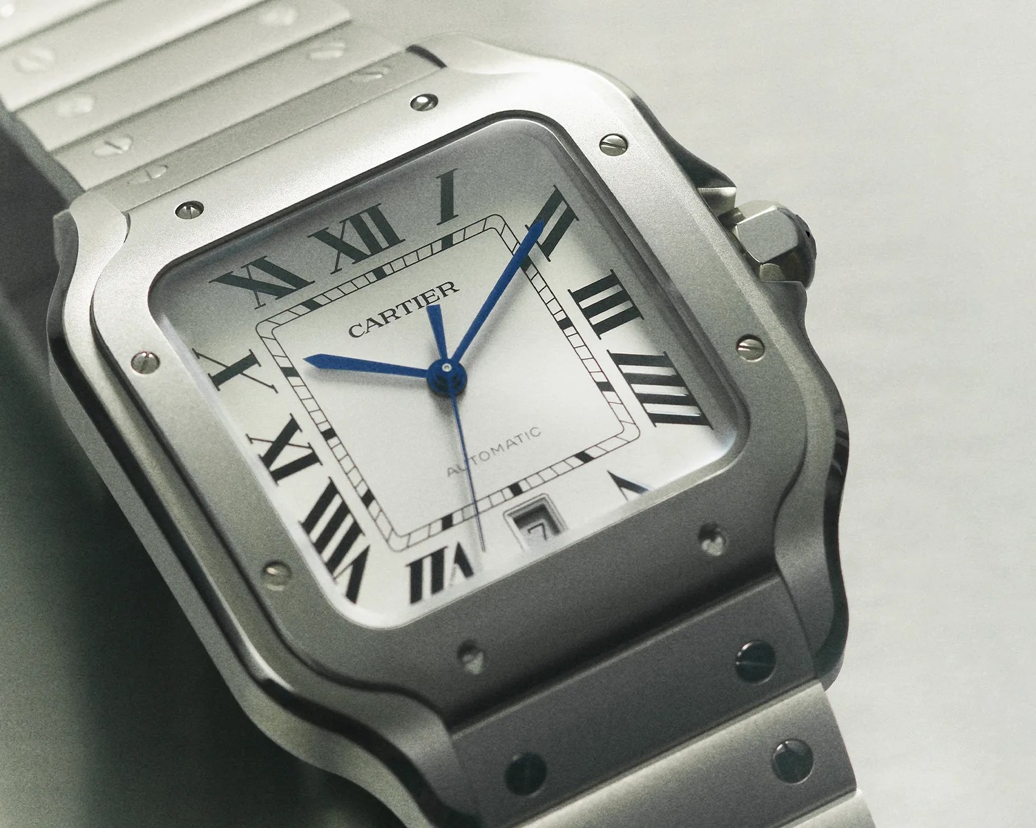 Square silver Cartier wristwatch with blue hands, Roman numerals, and a metal bracelet.