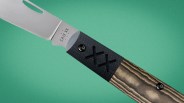 Knife with a stainless steel blade and a handle combining black textured material with wood grain finish.