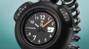 Black Casio stopwatch with white and orange hands and a coiled black cord attached.