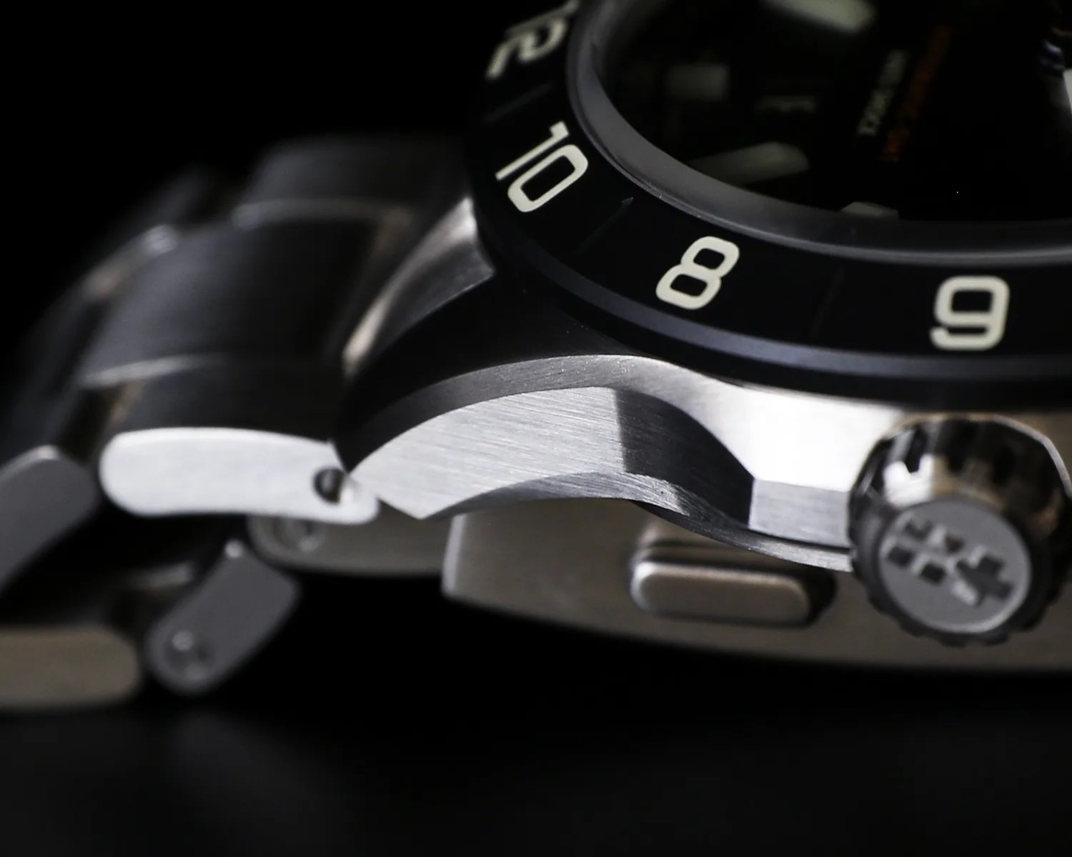 Close-up of a stainless steel watch case and bracelet with a black bezel showing numbers 8, 9, and 10.