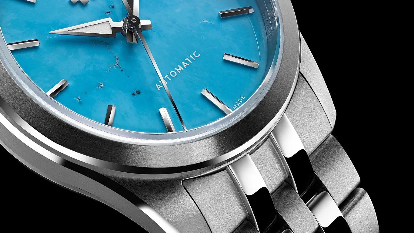 Close-up of a silver metal wristwatch with a turquoise marble-patterned dial and silver hour markers and hands.