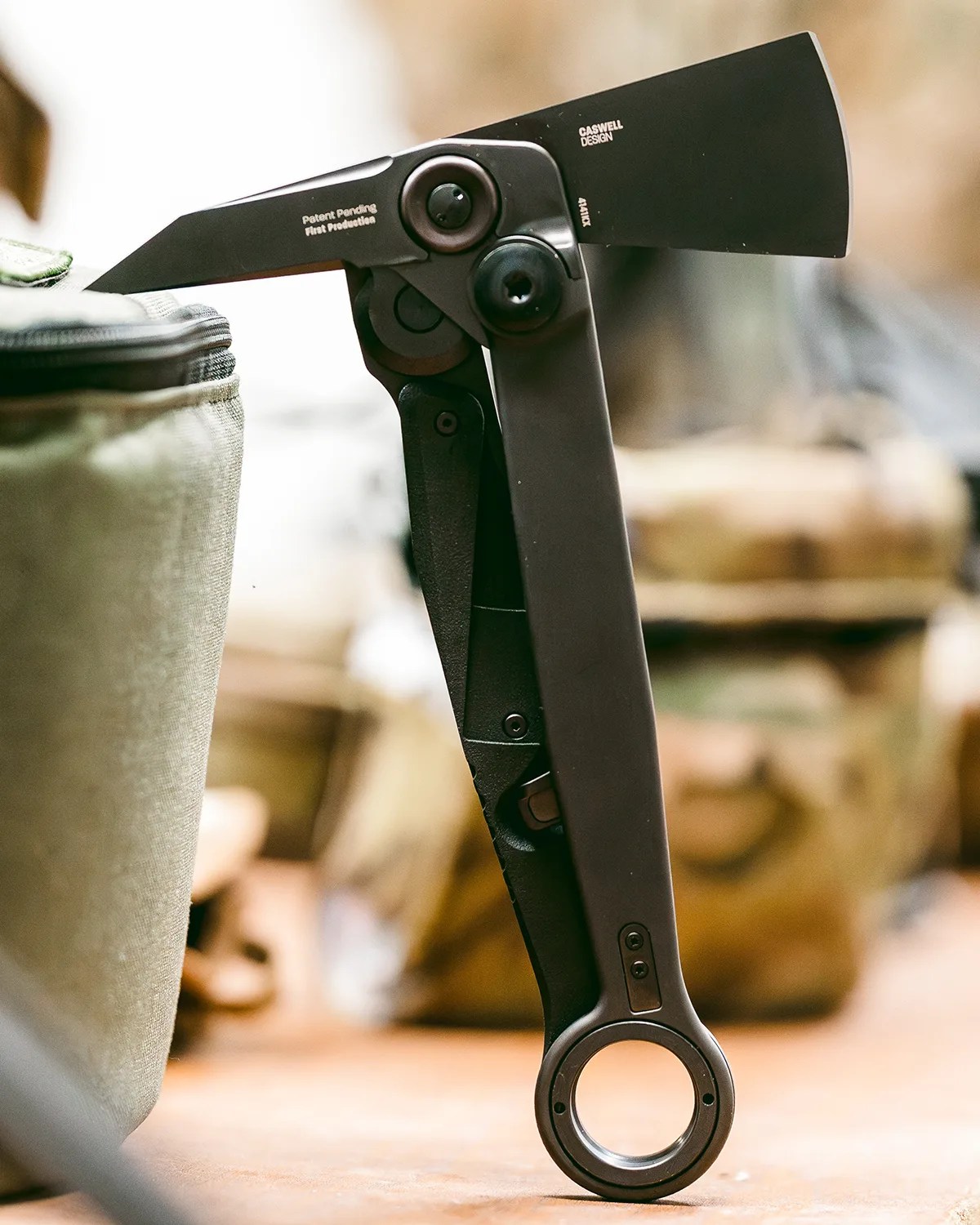 Black folding pocket knife with a cleaver-style blade and circular handle hole standing upright on a surface.