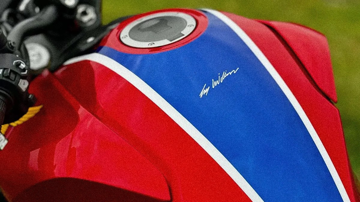 Red motorcycle fuel tank with a blue and white stripe and a silver fuel cap.
