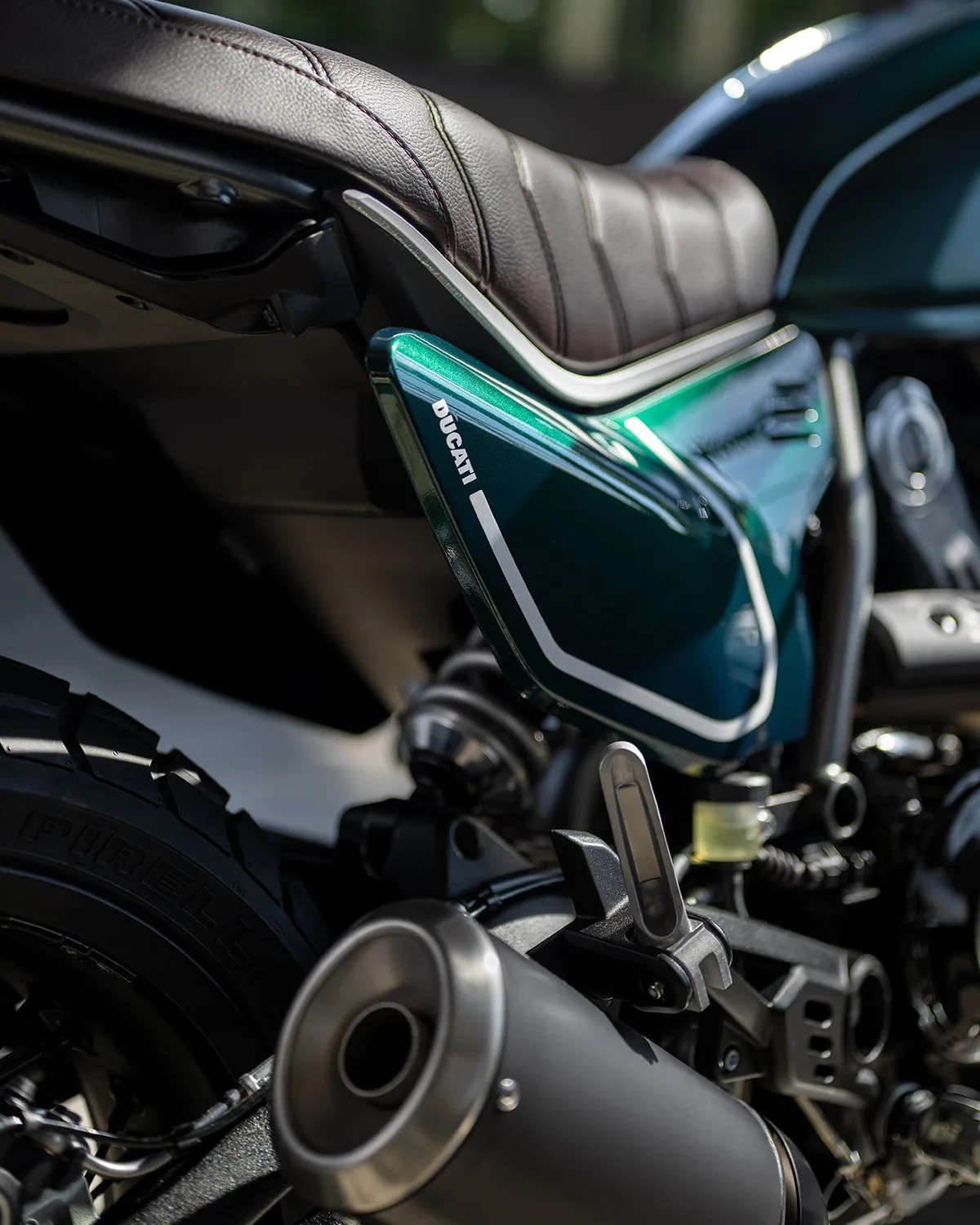 Close-up of a green Ducati motorcycle seat and rear exhaust with visible Pirelli tire.