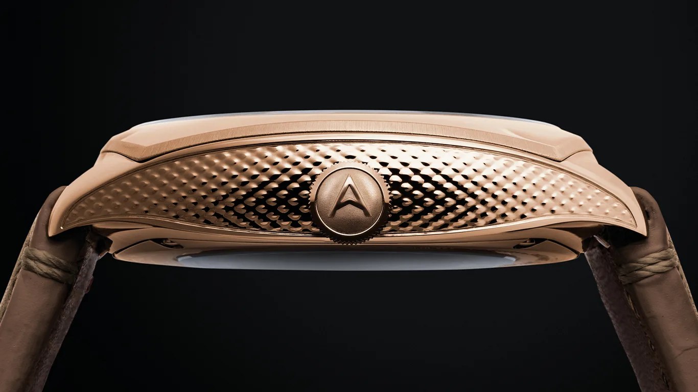 Side view of a rose gold watch case with a textured pattern and a crown featuring an embossed "A" logo.
