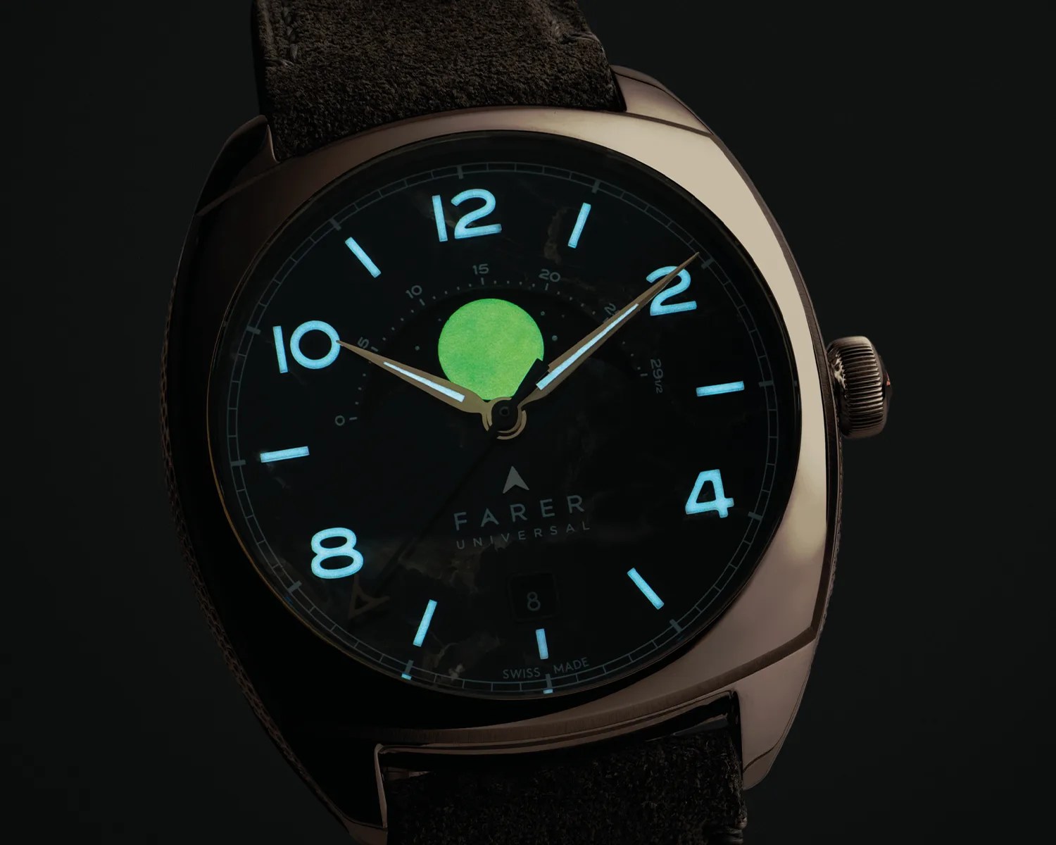 Close-up of a Farer Universal watch face with glowing blue numerals and hands, a green moon phase indicator, and a black leather strap.
