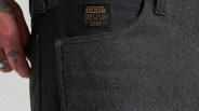 Close-up of black denim pants pocket with a black and gold Filson brand label and a tattooed hand nearby.