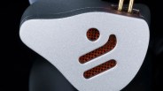 Close-up of a silver metallic device with a perforated orange grille and two gold connectors on top.